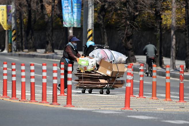 지난 3월 대구에서 한 노인이 폐지를 가득 실은 수레를 밀며 길을 건너고 있다. 뉴스1