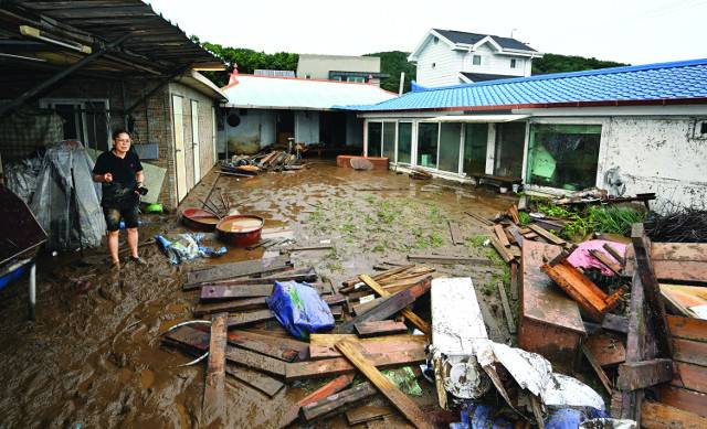 10일 새벽 폭우가 쏟아진 대전 서구 용촌동 정뱅이마을 주민이 토사와 함께 밀려든 나무판을 망연자실한 표정으로 바라보고 있다. 정뱅이마을 주민들은 새벽 4시쯤 마을 입구 갑천 제방이 무너지면서 물이 밀려들었다고 설명했다. 대전=윤웅 기자