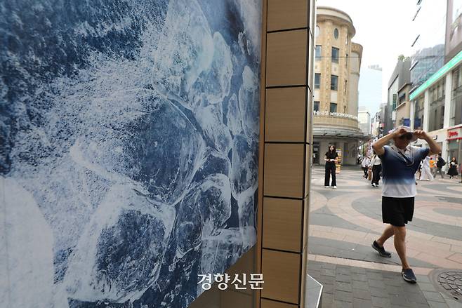 서울 명동의 한 상점에 걸린 얼음 사진 옆으로 12일 한 시민이 지나가고 있다. 김창길기자