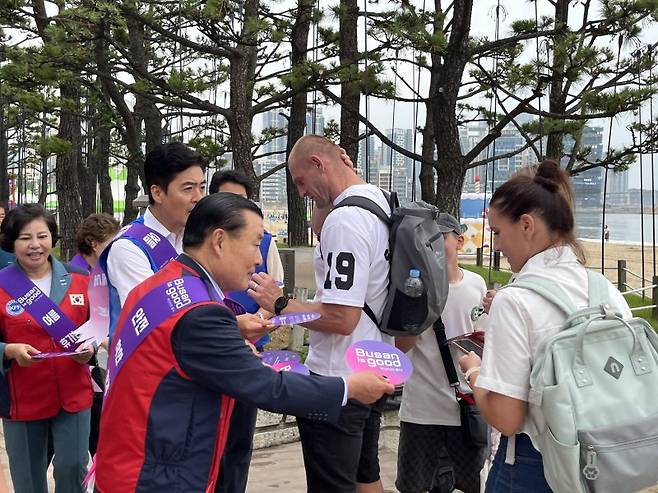 신한춘 한국자유총연맹 부산광역시지부 회장(왼쪽)이 광안리해수욕장을 찾은 외국인 관광객에게 부채를 나눠주고 있다. 한국자유총연맹 부산광역시지부 제공