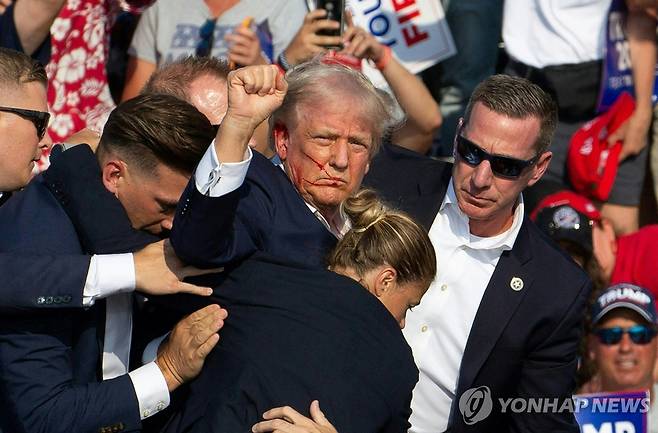 (버틀러 AFP=연합뉴스) 도널드 트럼프 전 미국 대통령이 13일(현지시간) 펜실베이니아 버틀러에서 열린 유세에서 총격을 받은 뒤 피를 흘리며 경호원들에게 둘러싸여있다. 2024.7.13 photo@yna.co.kr