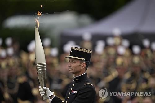 파리 들어온 올림픽 성화 (파리 AP=연합뉴스) 2024 파리 올림픽 성화가 14일(현지시간) 프랑스 혁명기념일에 맞춰 파리에 들어왔다. 파리 첫 봉송 주자인 티보 발레트 전 마장마술 금메달리스트가 성화를 들고 행진하는 모습. 2024.07.14.