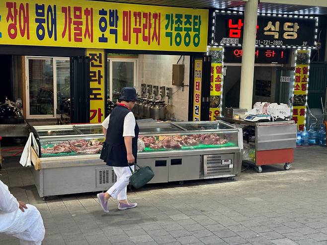 지난 14일 오후 모란시장 인근 건강원 앞에 마련된 개고기 매대를 지나는 시민의 모습. /양범수 기자