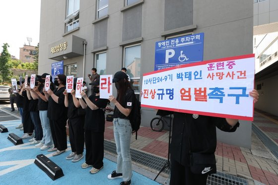 육군 12사단 훈련병 사망사건과 관련해 규정을 위반한 군기훈련(얼차려)을 실시한 중대장(대위)과 부중대장(중위)에 대한 구속 전 피의자 심문(영장실질심사)이 지난달 21일 오전 춘천지방법원에서 열린 가운데 군인 자녀를 둔 부모들이 엄벌을 촉구하는 피켓을 들고 서 있다. [연합뉴스]