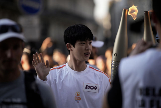 Jin carries the Olympic torch in Paris on July 14. [AP/YONHAP]