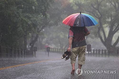 전국 곳곳에 비가 내린 16일 오후 서울 남산을 찾은 시민이 신발을 손에 들고 하산하고 있다. [연합뉴스]