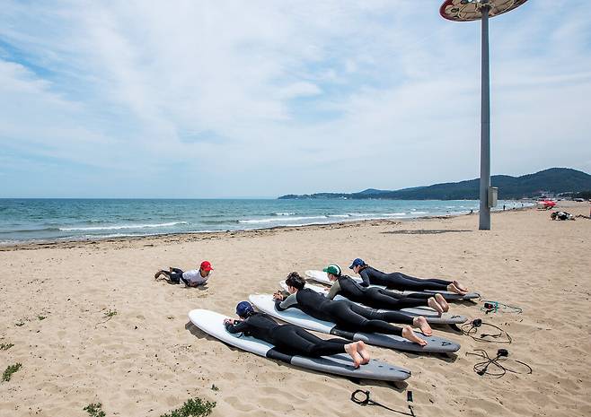 서핑 숍에서 이론 교육을 마친 수강생들이 모래사장으로 향했다. 바다에 들어가기 전 강사의 구호에 맞춰 실습을 한다. ⓒKTX매거진 신규철