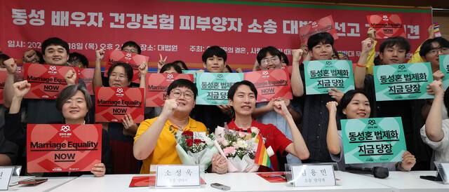 동성 배우자라는 이유로 건강보험 직장가입자인 배우자의 피부양자 자격을 박탈당했다며 국민건강보험공단을 상대로 소송을 낸 소성욱(왼쪽)씨와 배우자 김용민씨가 18일 오후 대법원 판결 뒤 서울 서초구 민주사회를 위한 변호사 모임 대회의실에서 열린 기자회견에 참석해 기념사진을 찍고 있다. 김정효 기자 hyopd@hani.co.kr
