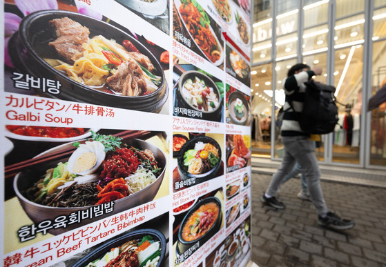 A passerby walks behind a restaurant menu in Jung District, central Seoul [NEWS1]