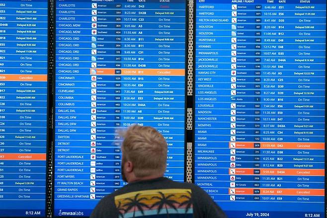 WASHINGTON, DC - JULY 19: A traveler checks flight information at Ronald Regan Washington National Airport on July 19, 2024 in Washington, DC. A global computer outage started from an update from the cybersecurity company CrowdStrike that impacted flights worldwide along with disrupting broadcasters and banking services. Nathan Howard/Getty Images/AFP (Photo by Nathan Howard / GETTY IMAGES NORTH AMERICA / Getty Images via AFP)