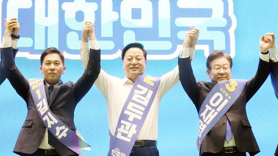 더불어민주당 새 지도부 선출을 위한 전당대회를 앞두고 20일 제주시 한라체육관에서 열린 합동연설회에서 김지수·김두관·이재명 대표 후보(왼쪽부터)가 손을 맞잡고 포토타임을 갖고 있다. 연합뉴스