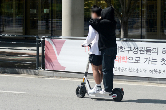 전주 전북대 교정에서 안전장비를 착용하지 않은 학생 두명이 전동 킥보드 한대에 타고 있는 모습. 뉴시스