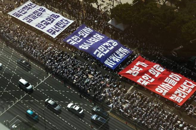 대한의사협회의 주도로 개원의와 일부 의대 교수들이 집단휴진에 나선 지난달 18일 오후 서울 영등포구 여의대로에서 열린 전국 의사 총궐기대회에서 의사들이 '의료농단' 등 문구가 적힌 대형현수막을 펼치고 있다.[이미지출처=연합뉴스]