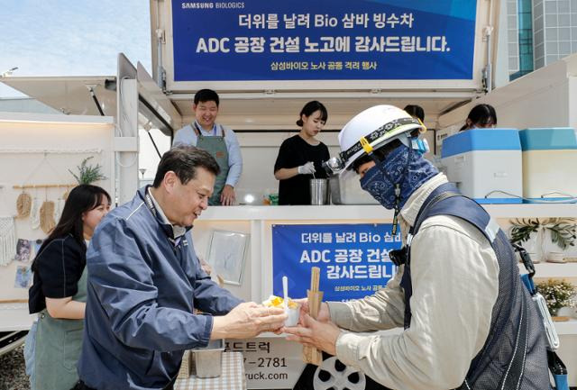 이규호(왼쪽) 삼성바이오로직스 피플센터 센터장이 지난 19일 협력사 기술인에게 빙수를 전달하고 있다. 삼성바이오로직스 노사는 이날 인천 송도 ADC 공장 건설 현장에서 협력사 기술인 900여 명을 대상으로 빙수와 추러스를 제공하는 상생협력 행사를 개최했다. 삼성바이오로직스 제공