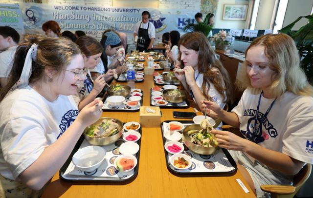 이달 11일 서울 성북구 한성대학교에서 열린 초복맞이 외국인 유학생 대상 삼계탕 나눔 행사에서 외국인 유학생들이 삼계탕을 맛보고 있다. 뉴스1