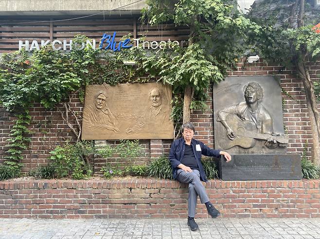 Singer-songwriter Kim Min-gi poses for a photo in front of the Kim Kwang-seok memorial stone at the Hakchon Blue Theater in Jongno-gu, Seoul. (Hakchon)