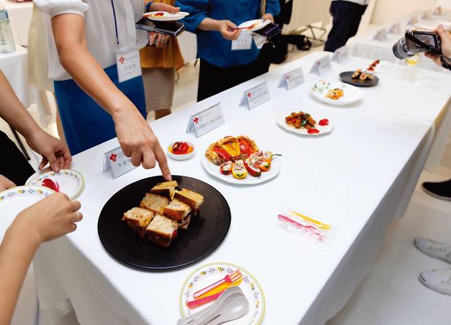 심사위원들이 완성된 요리를 시식하며 평가하고 있다.