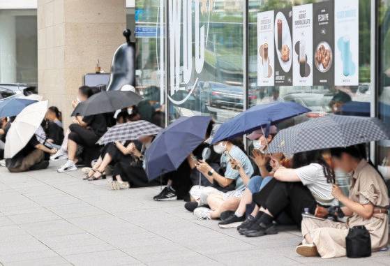 25일 서울 강남구 티몬 본사 앞에서 환불을 원하는 피해자들이 우산을 쓰고 사측을 기다리고 있다. 연합뉴스