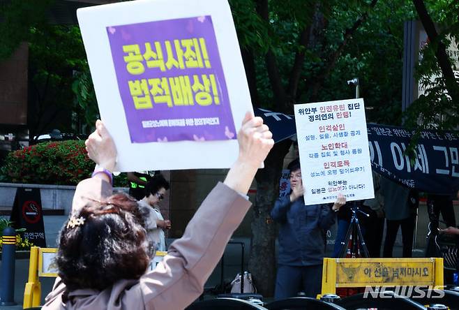 [서울=뉴시스] 김근수 기자 = 지난 1일 서울 종로구 주한일본대사관 인근에서 열린 일본군성노예제 문제해결을 위한 정기 수요시위에서 한 참가자가 수요시위 반대집회 중인 시민을 향해 손팻말을 들고 있다. 2024.05.01. ks@newsis.com