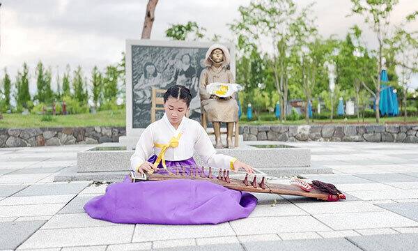 세종시의 한 학생이 소녀상에 꽃을 전달한 뒤 국악을 연주하고 있다. 경기도 제공