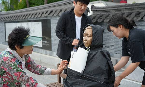 충남 예산의 캠페인 참여자들이&nbsp;비를 맞는 소녀상에 우의를 입히고 있다. 경기도 제공