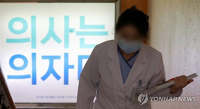 '의사는 의자다' (대구=연합뉴스) 윤관식 기자 = 의정갈등이 계속되고 있는 14일 대구 한 2차 병원에 '의사는 의자다'라는 홍보물이 게시된 가운데 의료관계자가 이동하고 있다. 2024.6.14 psik@yna.co.kr