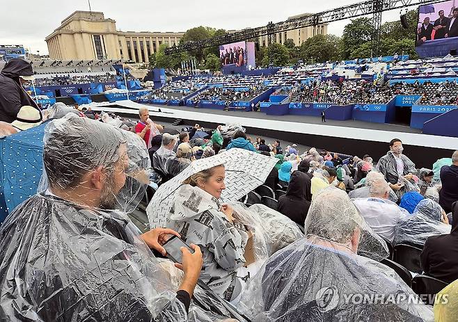 파리올림픽 개회식 앞두고 내리는 비 (파리=연합뉴스) 황광모 기자 = 2024 파리올림픽 개막일인 26일(현지시간) 프랑스 파리 트로카데로광장에 설치된 개회식장에서 비가 내리자 관객들이 우산과 우의를 쓴 채 개막식을 기다리고 있다. 2024.7.27 hkmpooh@yna.co.kr