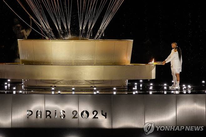 파리 올림픽 개회식 성화 최종 점화자는 페레크와 리네르 (파리 AFP=연합뉴스) 페레크와 리네르가 27일(한국시간) 프랑스 파리의 튈르리 정원에 있는 '열기구 성화대'에 불을 붙이고 있다.