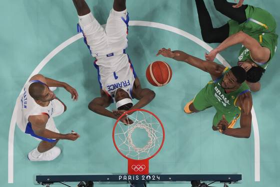Bruno Caboclo of Brazil grabs a rebound over Frank Ntilikina and Nicolas Batum of France in a men's basketball game at the 2024 Paris Olympics in Villeneuve-d'Ascq, France on Saturday. [AP/YONHAP]
