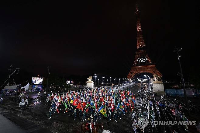 참가국 국기와 입장하는 오륜기 (파리=연합뉴스) 김도훈 기자 = 2024 파리올림픽 개회식이 열린 26일 오후(현지시간) 이에나 다리에 도착한 오륜기가 올림픽 참가국 국기와 함께 트로카데로 행사장으로 입장하고 있다. 2024.7.27 hkmpooh@yna.co.kr