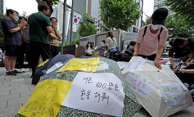 티몬과 위메프의 정산·환불 지연 사태가 지속되고 있는 28일 오후 서울 강남구 큐텐 본사 앞에서 피해자들이 사태 해결을 촉구하는 문구를 우산에 붙이며 시위를 준비하고 있다. 뉴스1