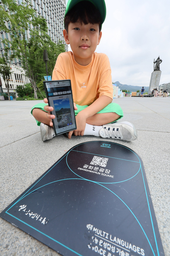 A child tries out an AI guide stamp tour at Gwanghwamun Square in Jongno District, central Seoul, on Tuesday. [YONHAP]