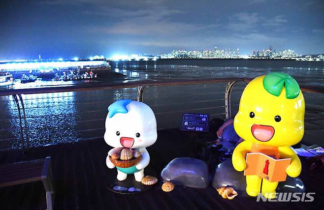[시흥=뉴시스] 박석희기자=빨간 등대 앞에 자리한 해로·토로 캐릭터 조형물이 조명등이 화려한 오이도 밤의 운치를 더하고 있다. 2024.7.30. photo@newsis.com *재판매 및 DB 금지
