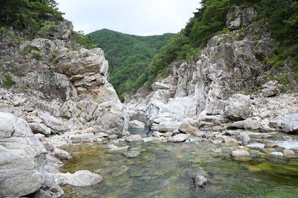 울진 왕피천 생태탐방로 2구간에서 취재팀이 바위 협곡인 용소와 하얀 용머리 바위를 보고 있다.