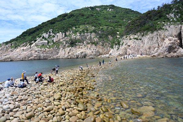 소매물도에서 등대섬으로 등산화를 벗고 몽돌 밭인 활목개를 건너는 등산객.