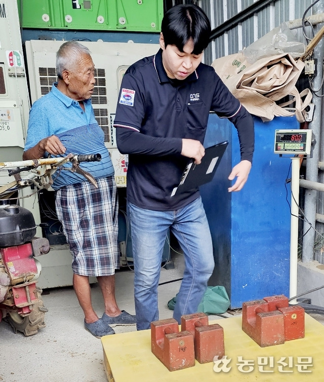 한국인정기구(KOLAS) 직원(오른쪽)이 한 농가에서 무게추를 이용해 톤백저울이 정확하게 측정하는지 점검하고 있다.