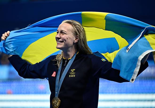 사라 셰스트룀이 1일 파리올림픽 수영 여자 자유형 100m에서 금메달을 딴 뒤 스웨덴 국기를 들고 기뻐하고 있다. 신화연합뉴스