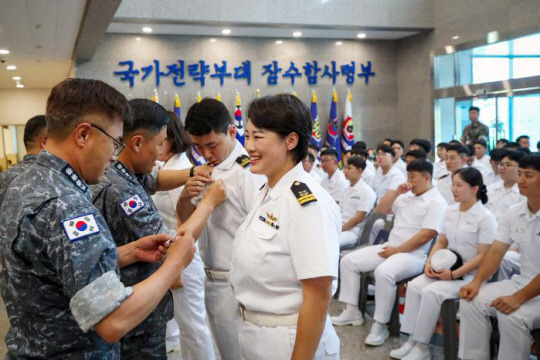 지난 2일 경남 진해 해군잠수함사령부 본관에서 열린 잠수함 휘장 통합수여식에서 홍승택(대령·맨 왼쪽) 91잠수함전대장이 도산안창호함 전투정보관 유효진(앞줄 왼쪽 두번째) 대위에게 금빛 돌고래 휘장을 달아주려 하고 있다. 국방일보 제공