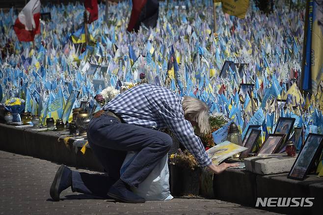 [키이우=AP/뉴시스] 23일(현지시각) 우크라이나 수도 키이우의 마이단 광장에 있는 전쟁 전사자 임시 추모소에서 한 남성이 무릎 꿇고 가족을 애도하고 있다. 전사자 가족이 꽂아놓은 우크라이나 국기에는 러시아군과 전투 중 숨진 군인의 이름이, 외국 국기에는 외국인 의용군의 이름이 표시돼 있다. 2024.07.24.