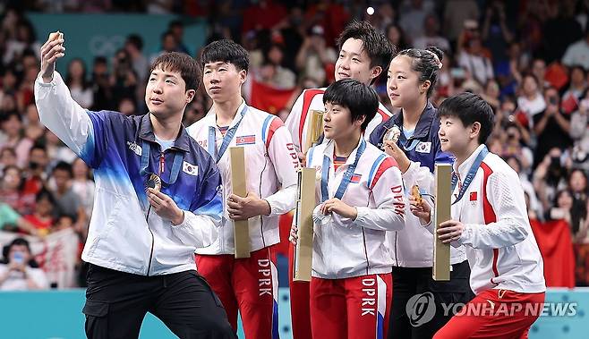 남북, 시상대에서 만나 '빅토리 셀피' (파리=연합뉴스) 김도훈 기자 = 30일(현지시간) 프랑스 파리 사우스 파리 아레나4에서 열린 2024 파리올림픽 탁구 혼합복식 시상식에서 동메달을 차지한 한국 임종훈, 신유빈과 은메달을 차지한 북한 리정식, 김금영 등이 시상대에서 삼성 Z플립 6로 함께 기념 촬영을 하고 있다. 2024.7.30 superdoo82@yna.co.kr