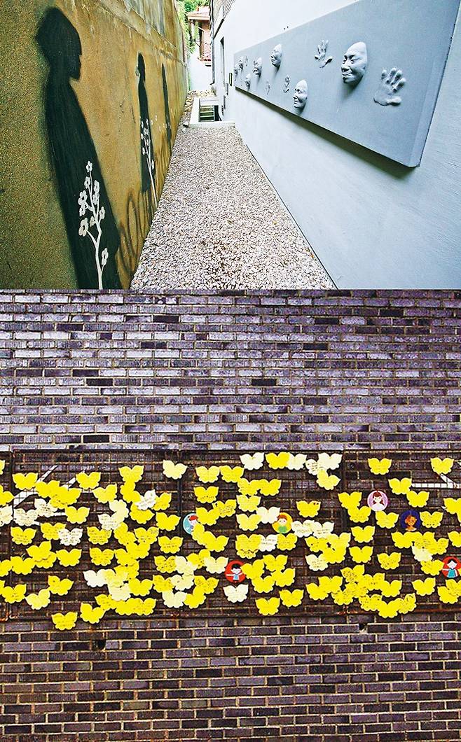 전쟁과여성인권박물관 지하전시실로 가는 길. 골목 한쪽 벽에 줄지어 끌려가는 소녀들의 모습이 그려졌고, 맞은편 벽에는 괴로운 얼굴로 그것을 보는 할머니들의 얼굴과 손 부조상이 설치됐다(전쟁과여성인권박물관 담장).