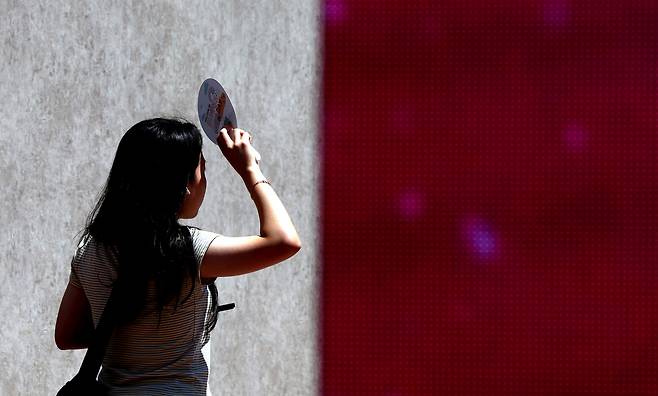 A pedestrian walks by while covering her face from the sun with a fan in Daegu, as daytime temperatures reached as high as 36 degrees Celsius on Monday. (Newsis)