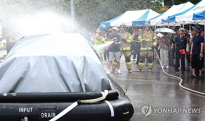 전기차 화재 진압 시연에 직접 참여한 주민 (인천=연합뉴스) 임순석 기자 = 13일 오전 인천 연수구 송도2동 행정복지센터 주차장에서 열린 전기자동차 화재대응 민·관 합동 교육에서 한 주민이 소방관들의 질식소화포와 전기차 수조탱크를 이용한 전기차 화재 진압 모의 시연에 참여하고 있다. 2024.8.13 soonseok02@yna.co.kr