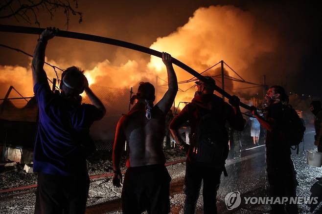 그리스 산불 (브릴리시아 AFP=연합뉴스) 12일(현지시간) 아테네 외곽 브릴리시아의 목재 공장에서 발생한 화재를 진화하는 소방관들을 돕기 위해 자원봉사자들이 소방 호스를 들고 있다. 2024.08.12 photo@yna.co.kr