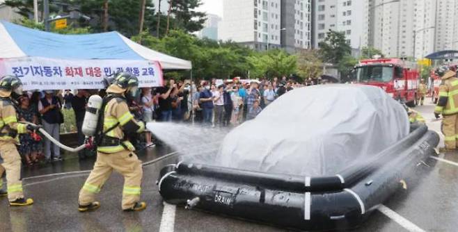 Firefighters are demonstrating a simulation of electric vehicle fires during a public-private joint training session held in a parking lot of Songdo 2-dong Administration and Welfare Center in Yeonsu-gu, Incheon on August 13.