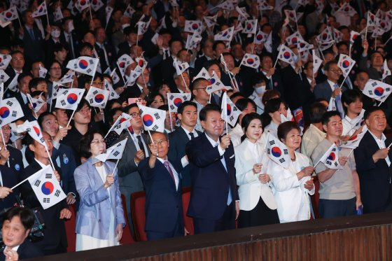 윤석열 대통령과 김건희 여사가 15일 서울 종로구 세종문화회관에서 열린 제79주년 광복절 경축식에서 이동일 순국선열유족회장 등 참석자들과 태극기를 흔들고 있다. 대통령실사진기자단