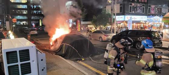 Firefighters work to extinguish a blaze that broke out from a Tesla on a road in Yongin, Gyeonggi. [NEWS1]