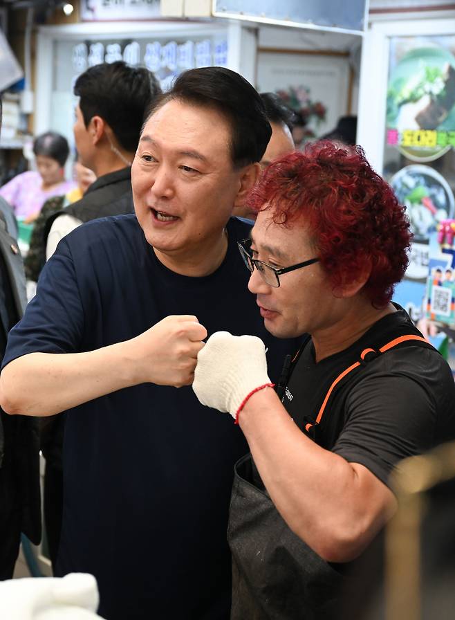 여름휴가 중인 윤석열 대통령이 5일 경남 통영시 통영중앙시장을 찾아 한 상인과 주먹을 맞대며 기념 촬영을 하고 있다. [연합]