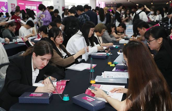 지난 5월 23일 오후 부산 해운대구 영화의전당에서 열린 '외국인 유학생 채용박람회'에서 외국인 유학생들이 이력서를 작성하고 있다./뉴스1