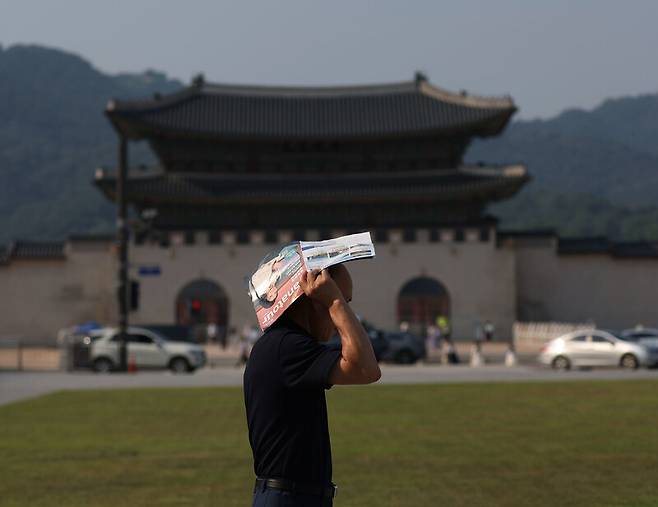 폭염 주의보가 발령된 지난 6월19일 오후 서울 광화문 거리를 찾은 한 시민이 광고지로 햇볕을 가리고 있다. 연합뉴스